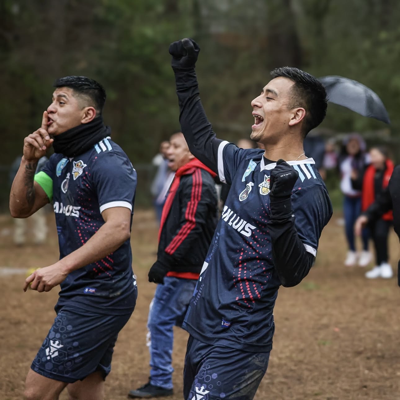 Players celebrate a goal in the rain